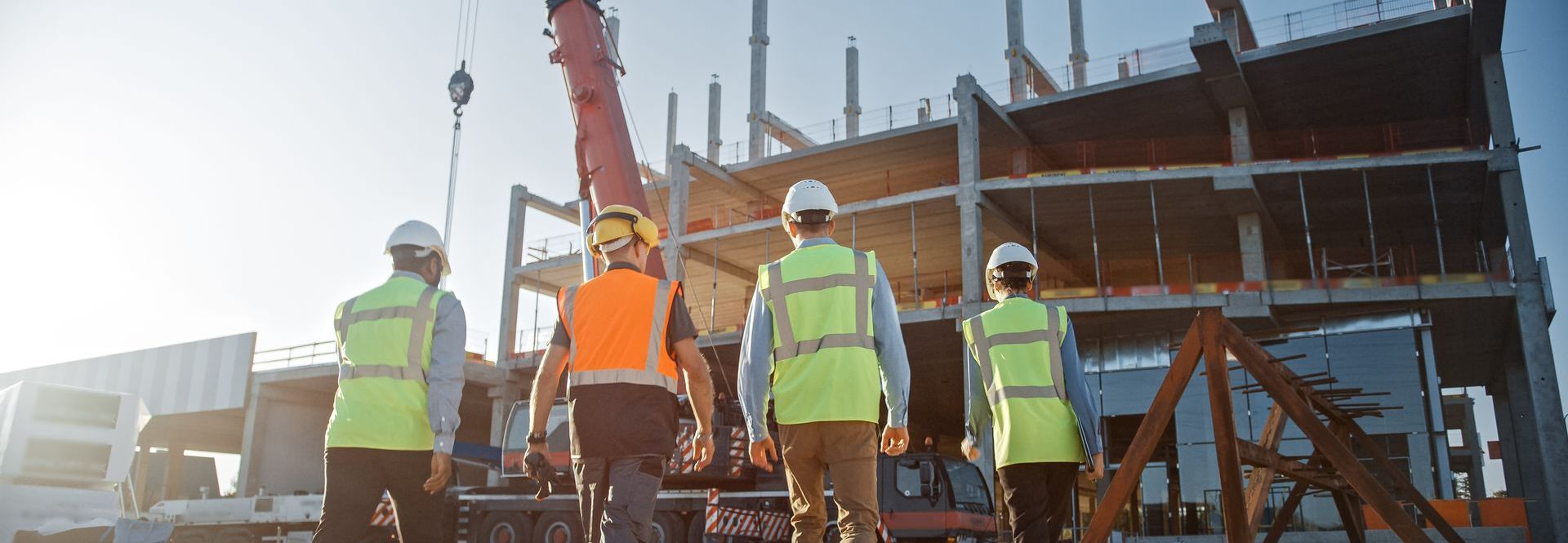 A group of construction workers are standing in front of a building under construction.