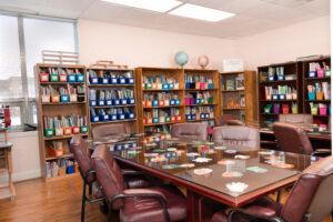 Conference room with large table, leather chairs, and bookshelves filled with binders.