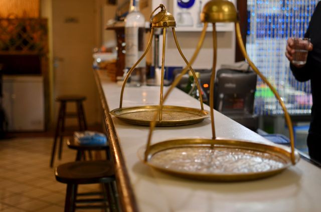 Tre vassoi da portata in ottone su un bancone in un ristorante illuminato da una luce calda.