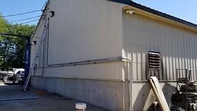 Cream-colored building with concrete base, ladder, and security camera on the side.