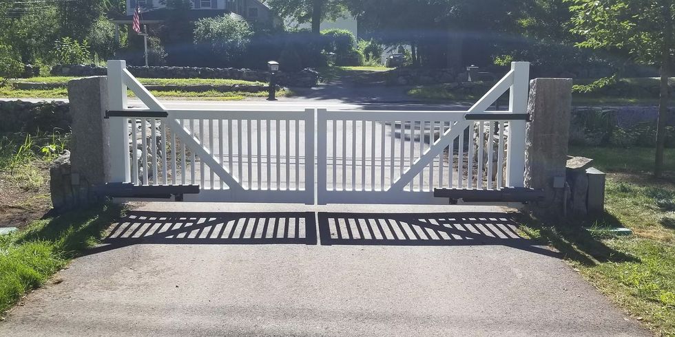 Person installing a security camera on a white wall, using a screwdriver.