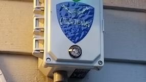 White "Click2Enter" access control box mounted on a beige house siding.