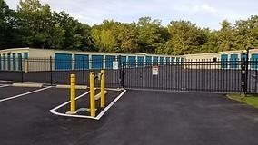 Storage units behind a black fence and a gated entrance.