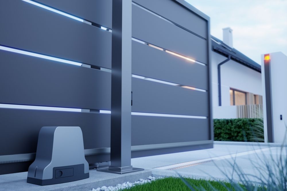 A sliding gray gate with a motor, set in front of a white house.