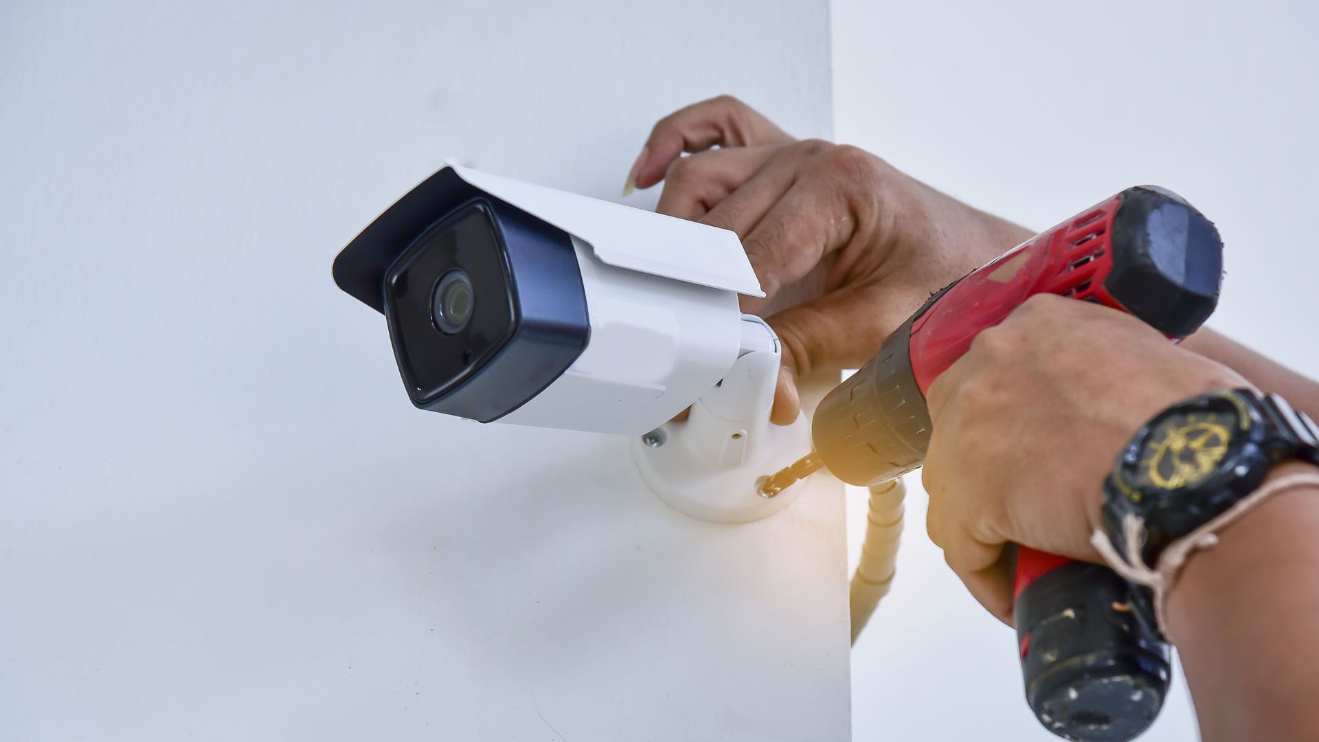 Garage door opener, black and gray casing, red light illuminated. Mounted on a ceiling.
