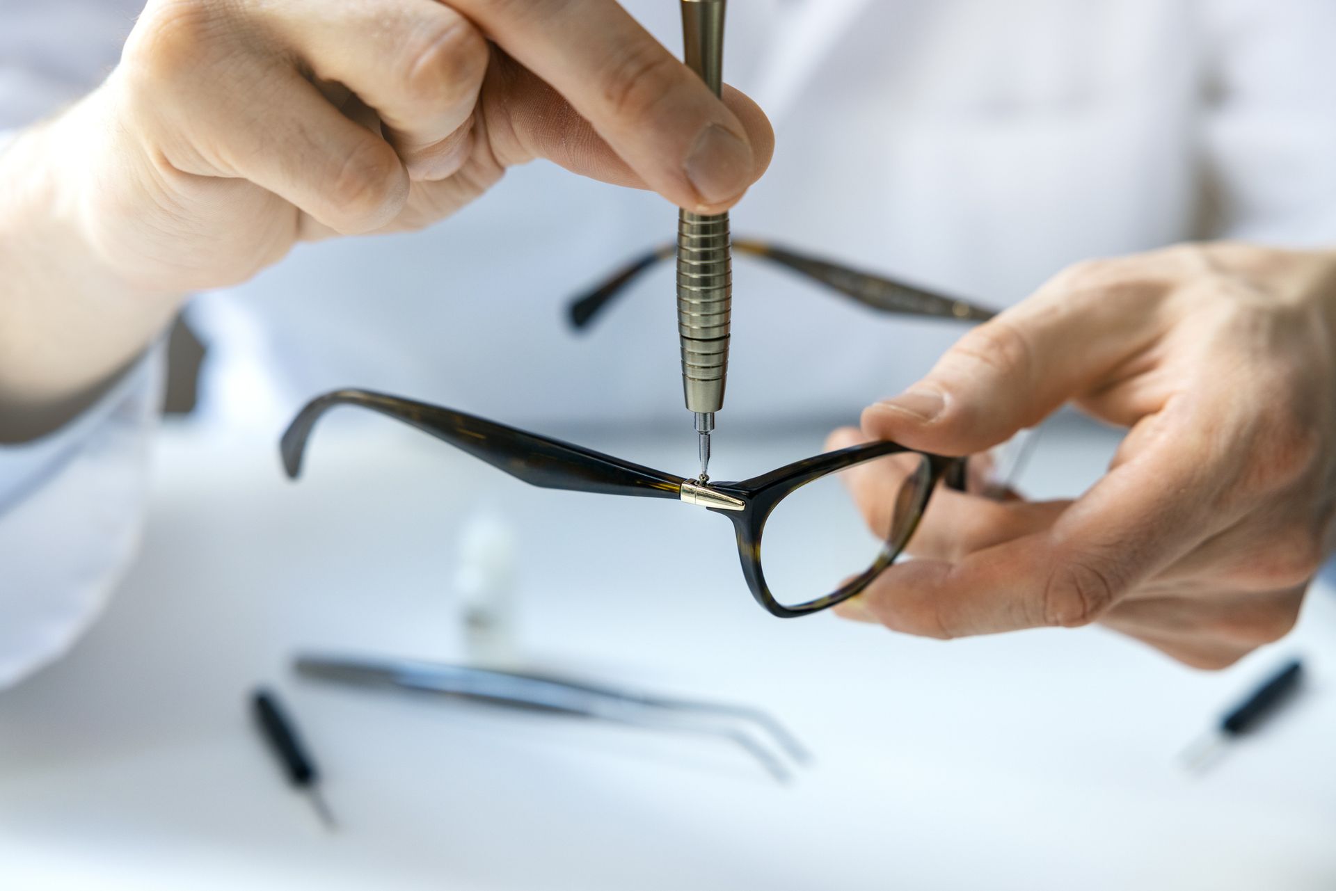 Person using a screwdriver to repair eyeglasses.