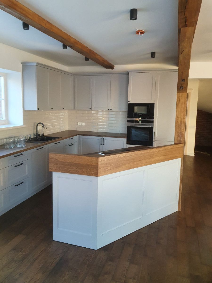 Virtuvė su baltomis spintelėmis ir mediniais stalviršiais