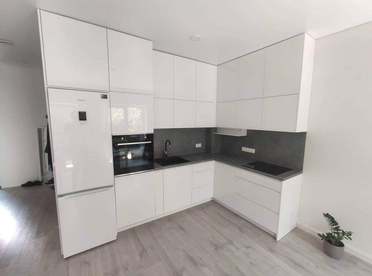 Virtuvė su baltomis spintelėmis, juodais stalviršiais