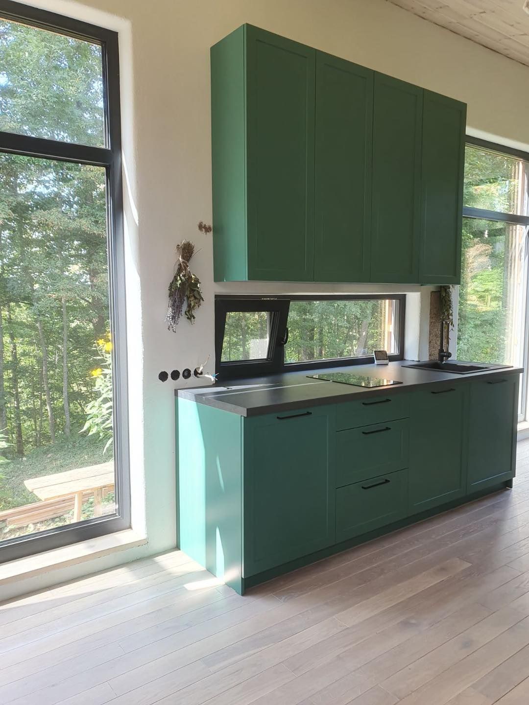 Virtuvė su žaliomis spintelėmis ir dideliu langu