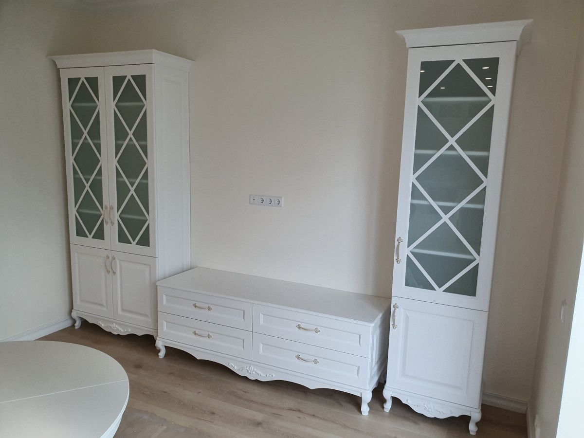 Svetainė su baltomis spintelėmis ir stalu