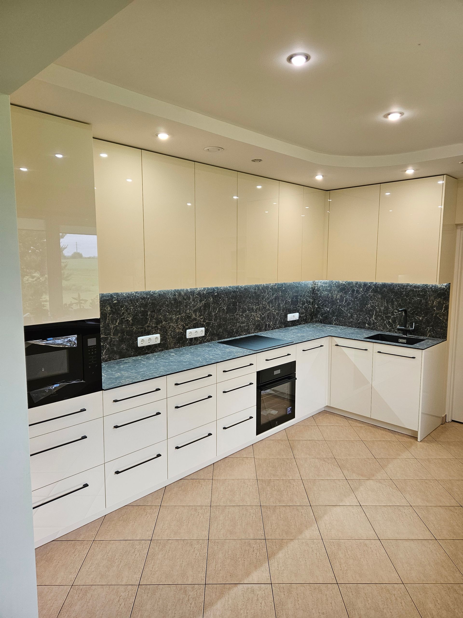 Virtuvė su baltomis spintelėmis ir juodais prietaisais