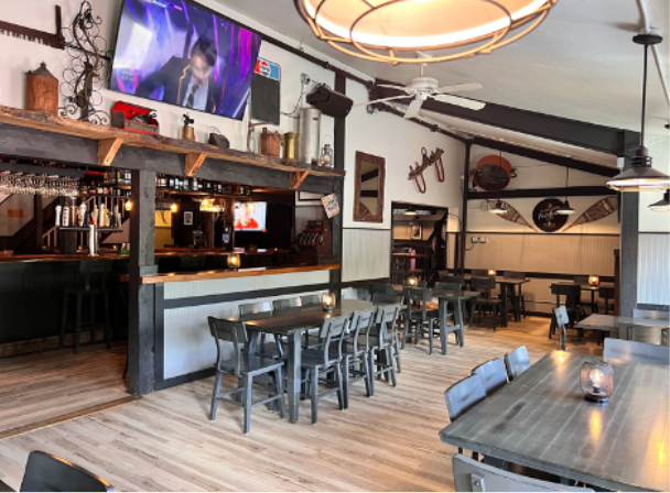 Interior of a bar and restaurant with wooden tables and a bar, neutral colors, and decorative elements.