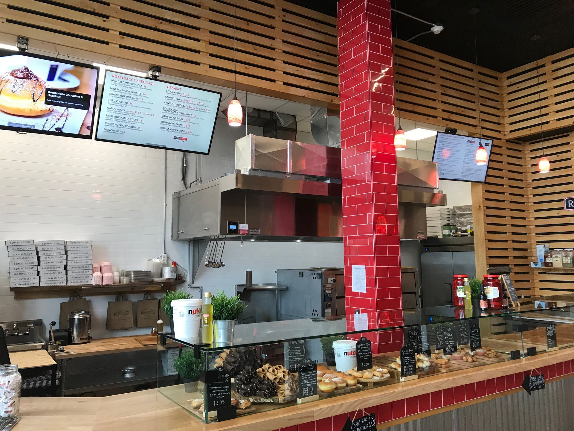 Interior of a restaurant with a red tiled pillar, food display, and menu screens.