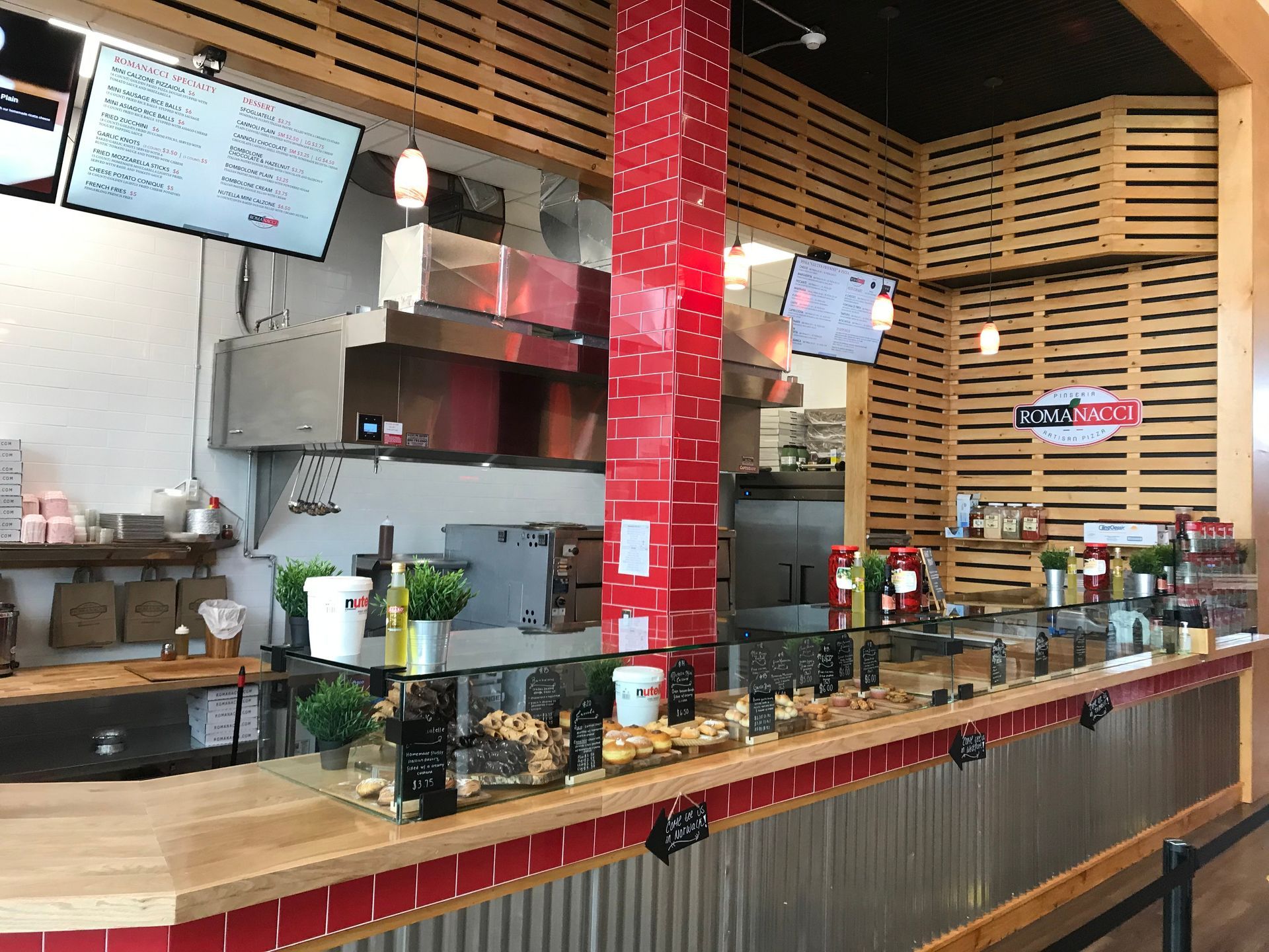 Interior of a restaurant with a wooden counter, red accents, and stainless steel appliances.
