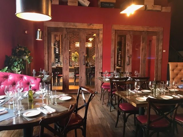 Elegant restaurant interior with red walls, wood accents, and tables set for dining.