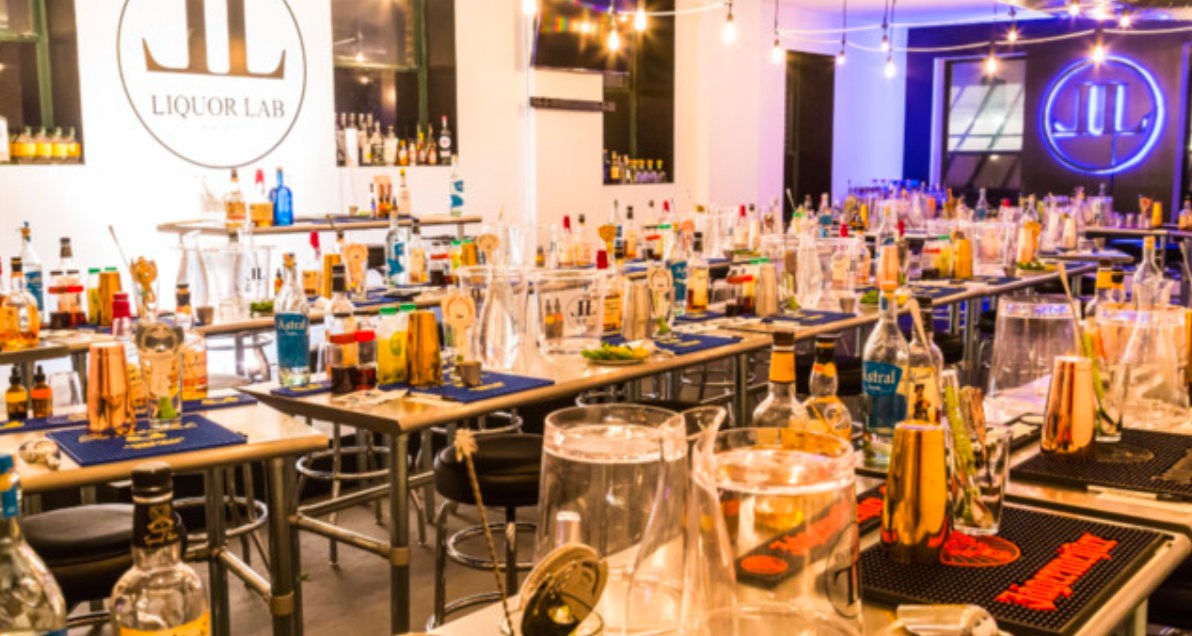 Cocktail class at Liquor Lab, with many bottles, glassware, and a neon logo.