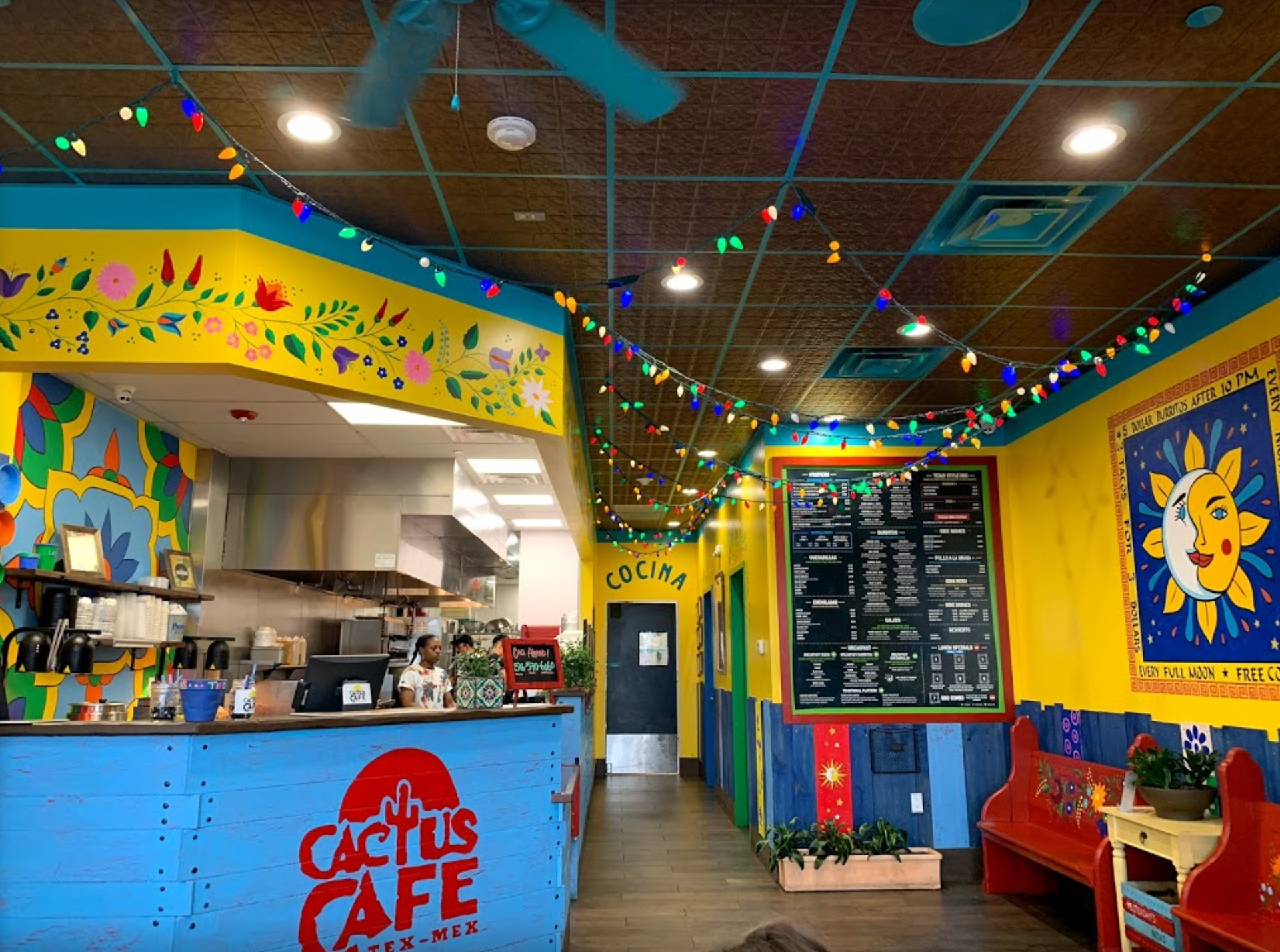 Inside Cactus Cafe: colorful Mexican restaurant interior with counter, menu, and decorations.