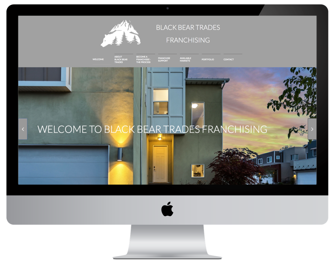 Computer screen displaying the Black Bear Trades Franchising website with a photo of a modern house at sunset.