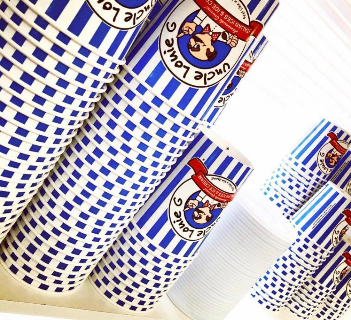 Stacks of Uncle Louie G’s blue and white striped paper cups, some with logo, close-up shot.
