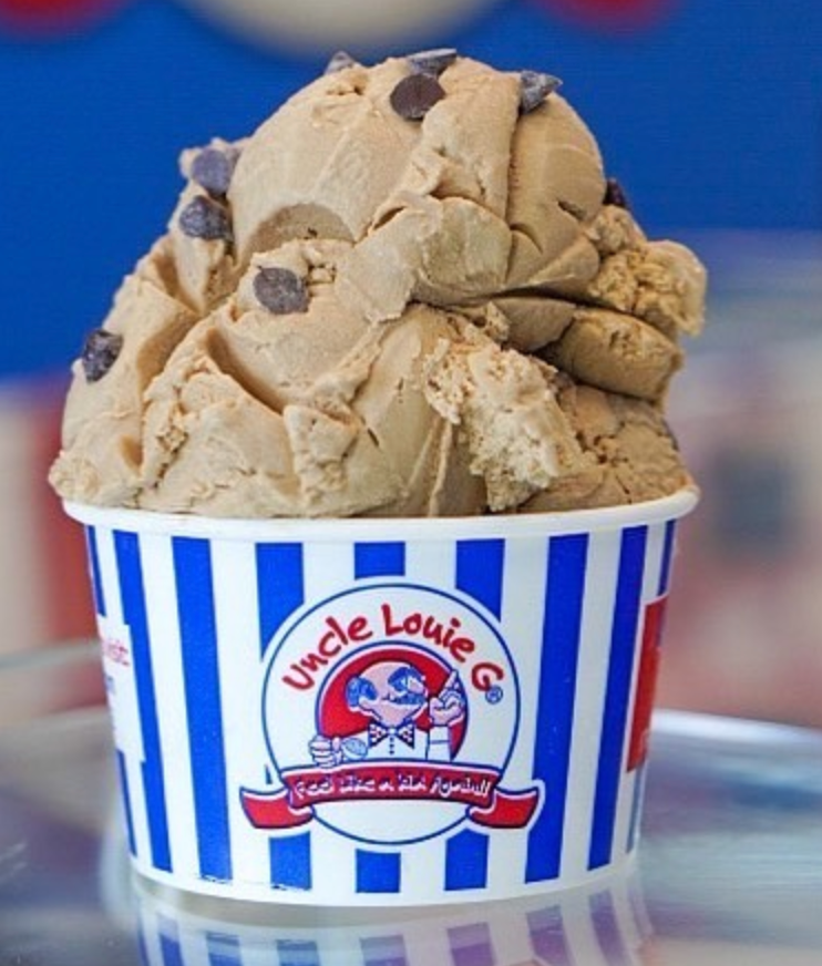 A scoop of ice cream with chocolate chips in a striped Uncle Louie G cup.