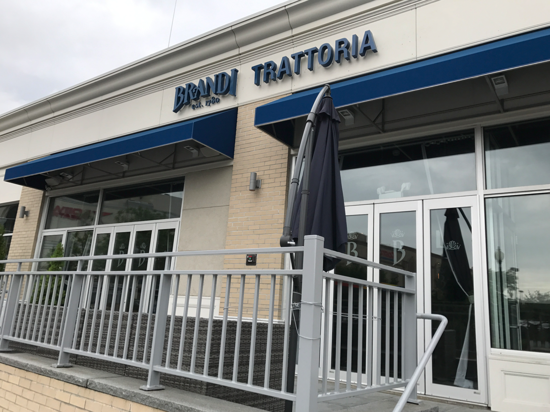 Exterior of Binni Trattoria restaurant with blue awnings and outdoor seating.