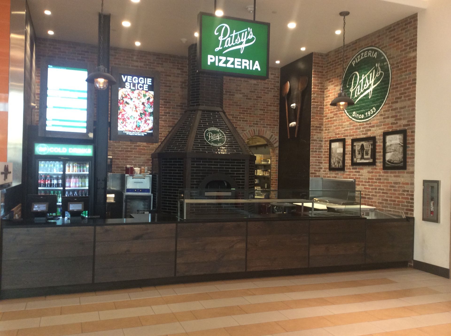 Patty's Pizzeria interior with brick oven, counter, and signs, in a mall setting.