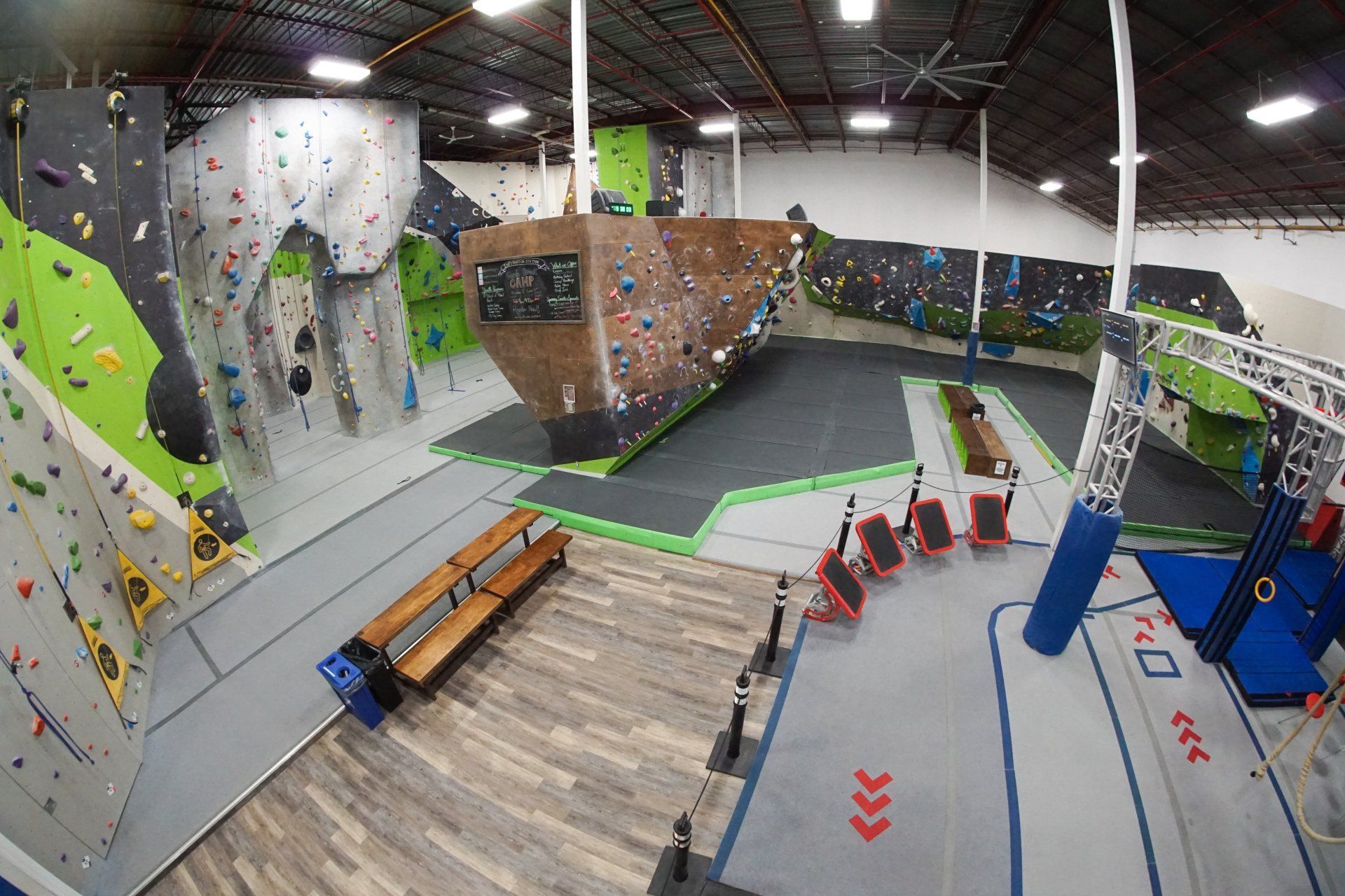 Indoor rock climbing gym with multi-colored climbing walls and crash pads.