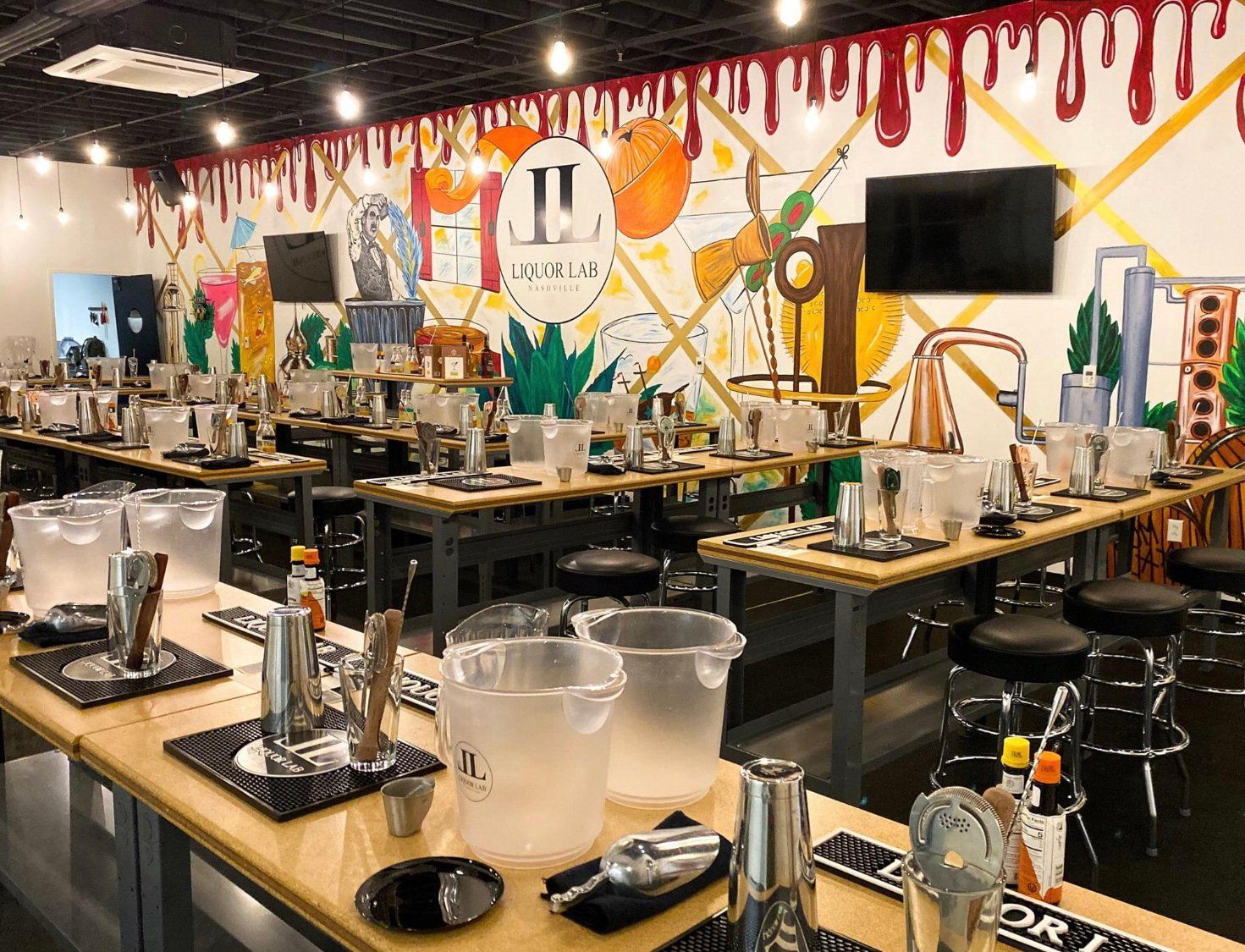 Cocktail-making class: Tables with bar tools, ice buckets, and a colorful mural backdrop.