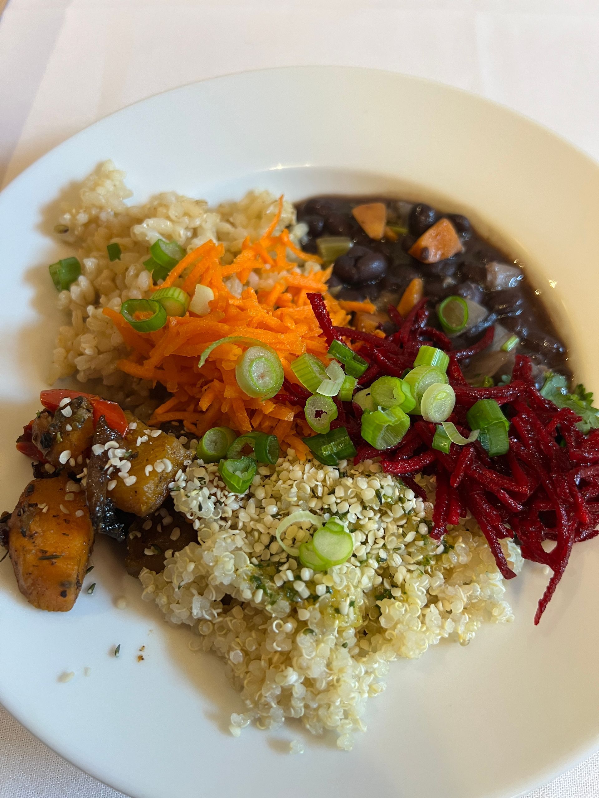 Plate of food with quinoa, shredded carrots and beets, beans, and scallions.