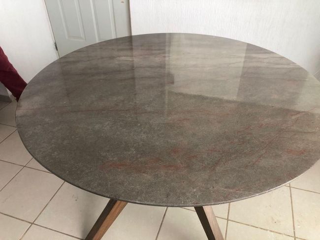 Una mesa redonda con tapa de mármol y patas de madera