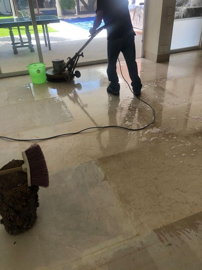 Un hombre está limpiando un piso de mármol con una máquina.