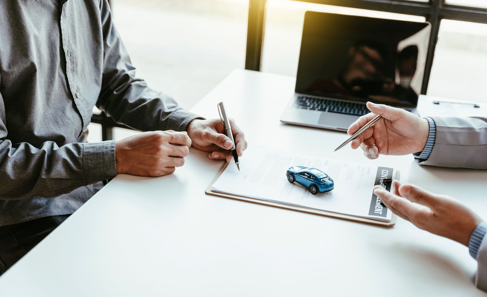 Businessman signing automobile insurance contract paperwork.