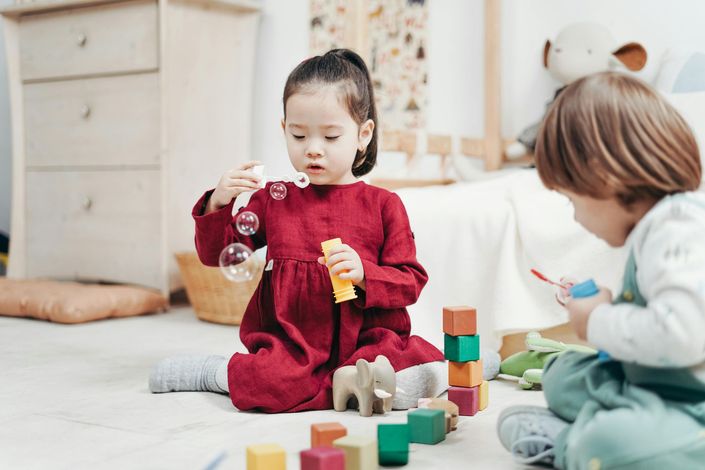 Children playing with wooden blocks on a light floor in a bright room