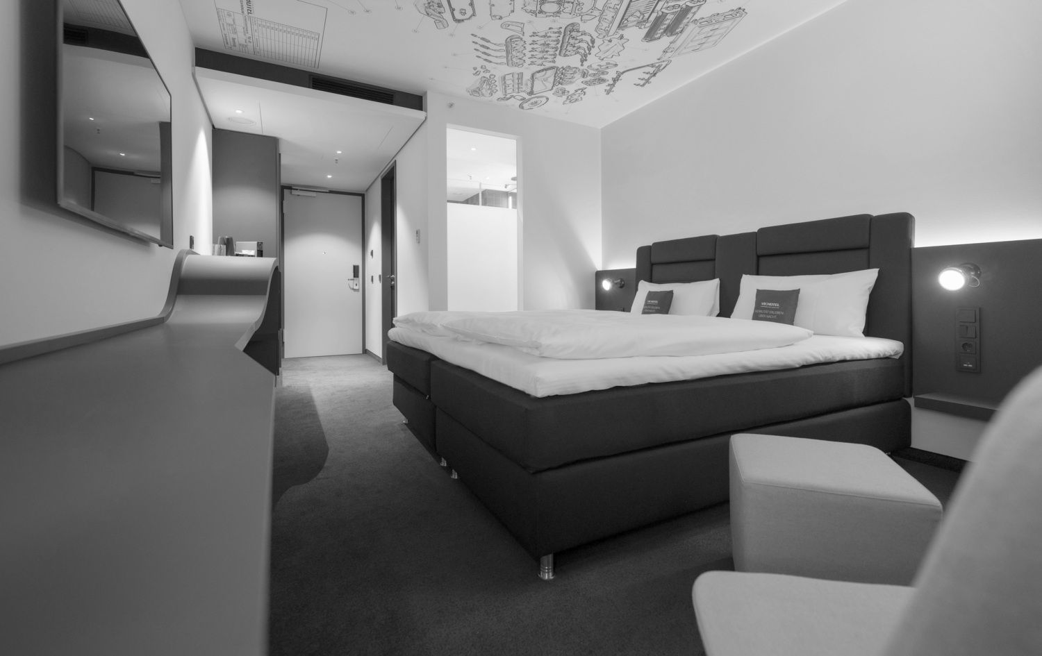 Modernes Hotelzimmer mit Bett, Wandfernseher, Schreibtisch und Balkontüren