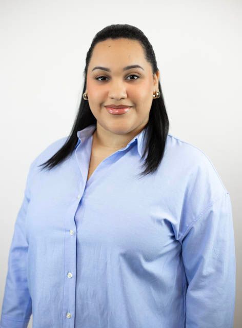 A woman in a blue shirt is smiling for the camera.