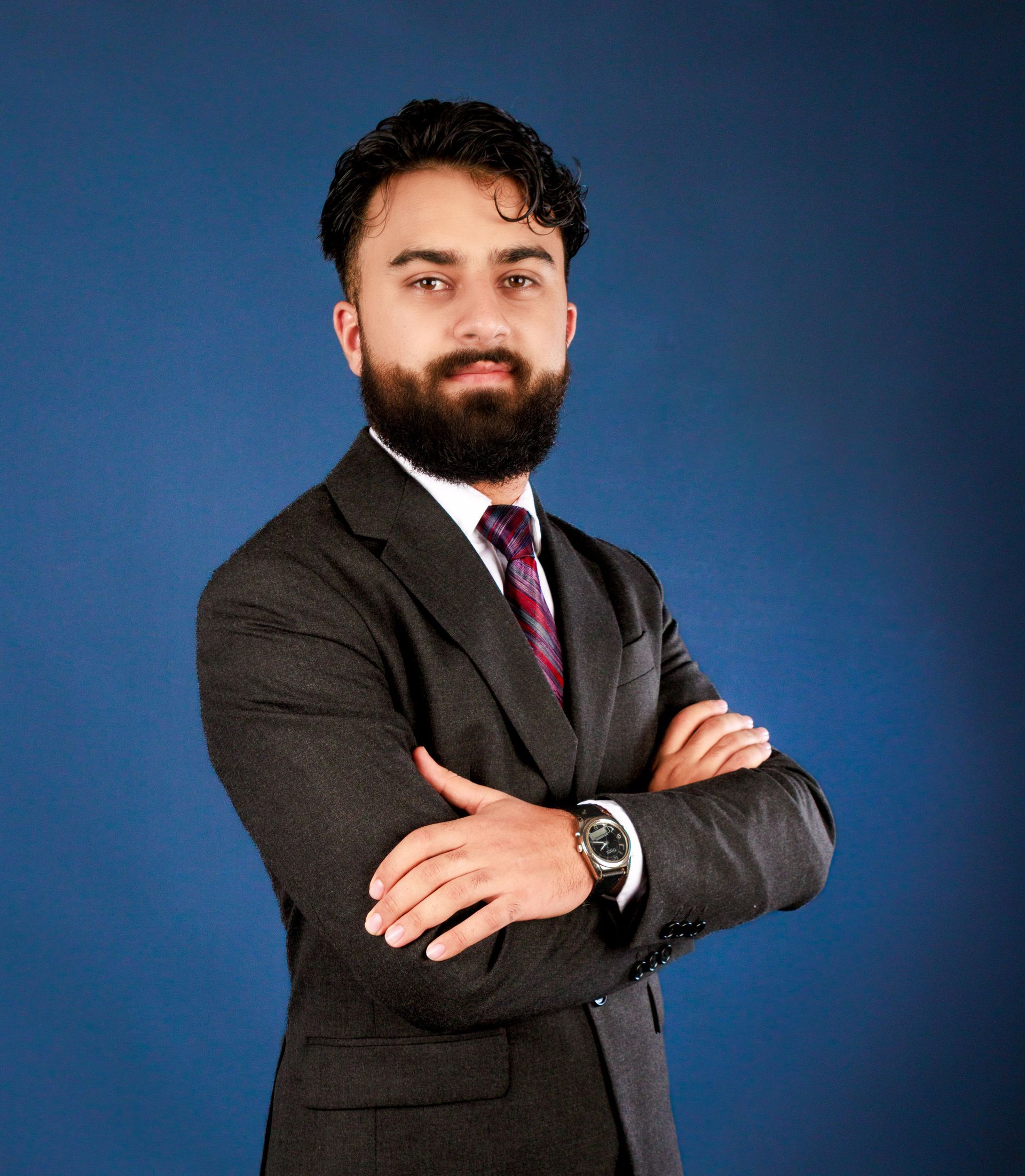 A woman in a blue shirt and black jacket is smiling for the camera.