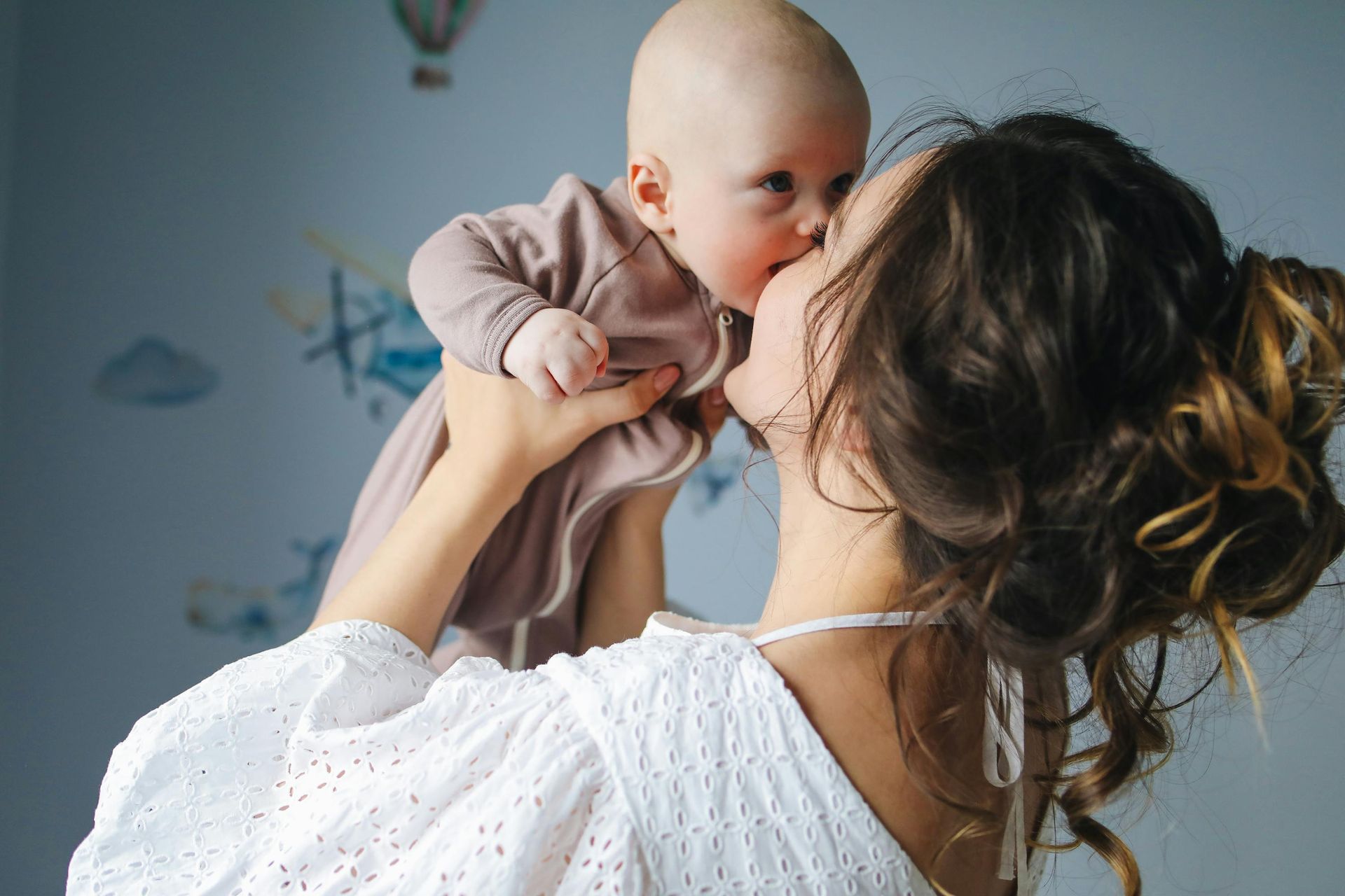 Vrouw met twee kinderen, kijkt naar beneden, lichtgroene en roze vormen op de achtergrond.