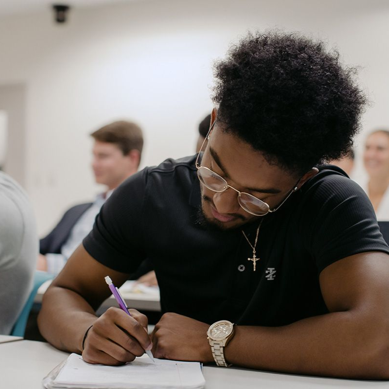 A musician plays acoustic guitar on stage, singing into a mic. A woman sings in the background. Dark stage, wood floor.
