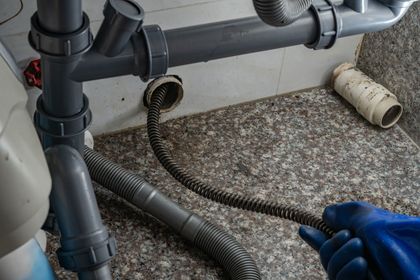 Plumber using a drain snake on a kitchen sink drain