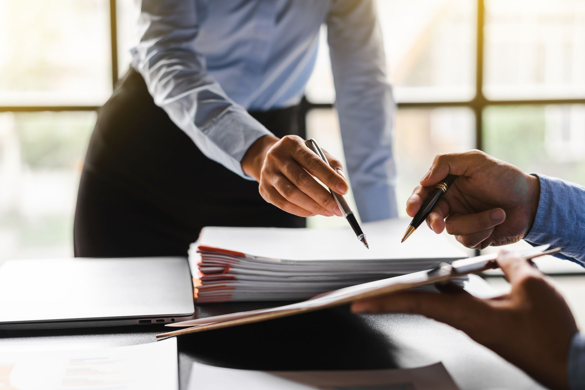 A man and a woman are sitting at a table holding pens.