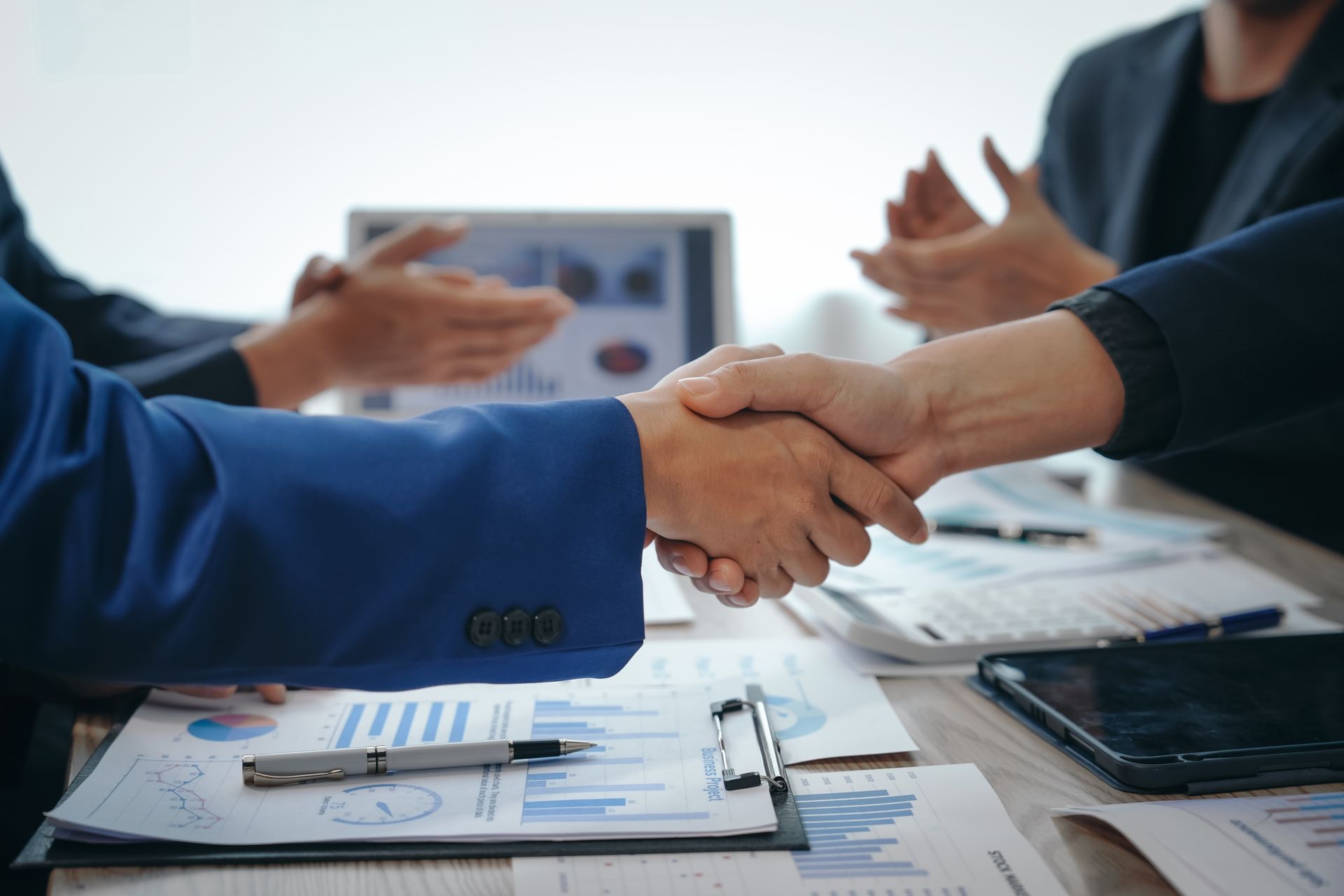 A group of business people are shaking hands at a table.