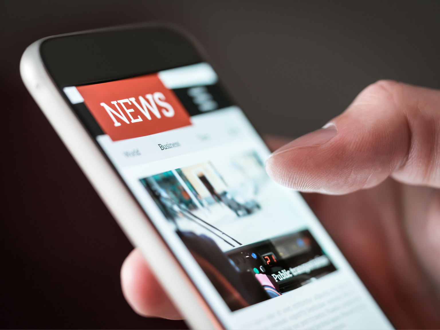 A person is holding a cell phone with news on the screen
