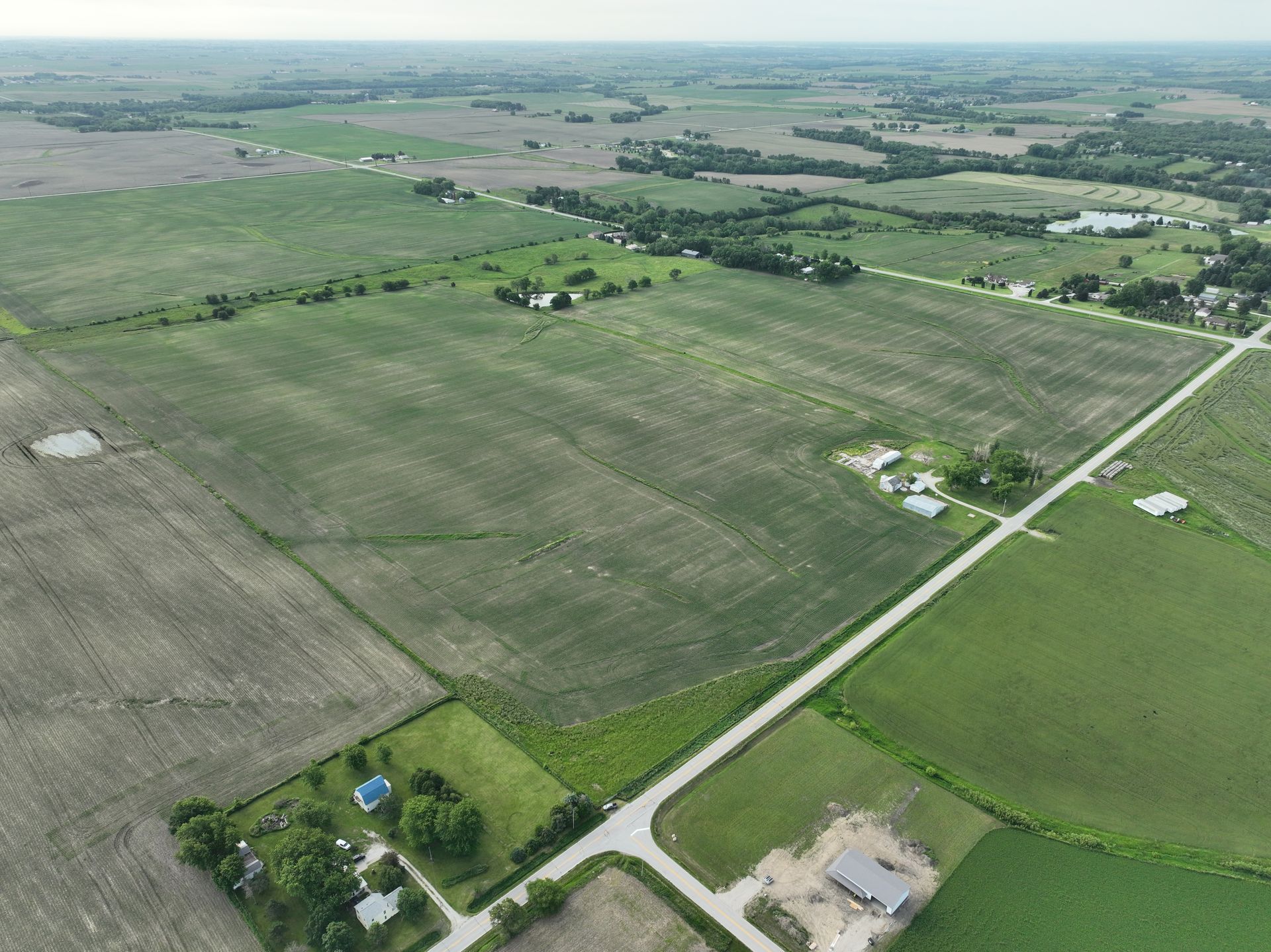 An aerial view of a lush green field with a house in the middle