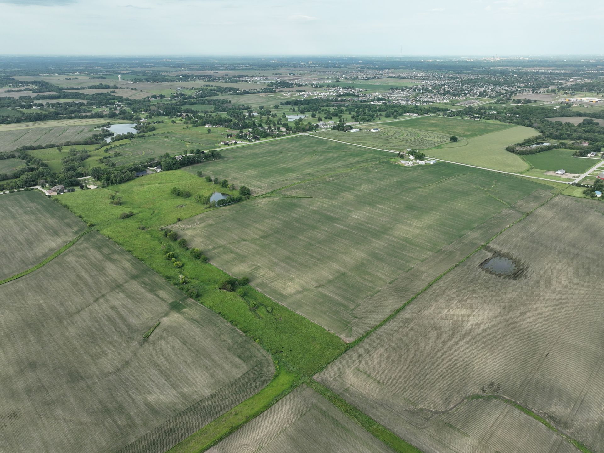 An aerial view of a field with a small pond in the middle