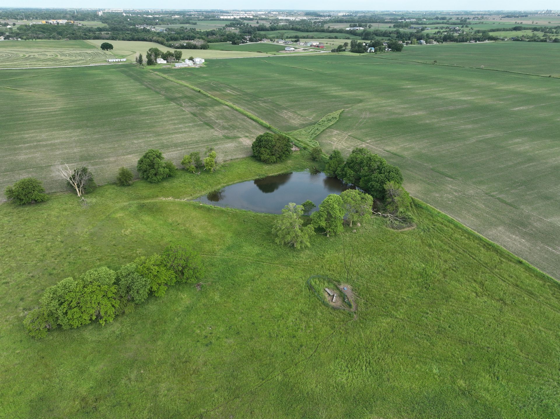An aerial view of a field with a small pond in the middle