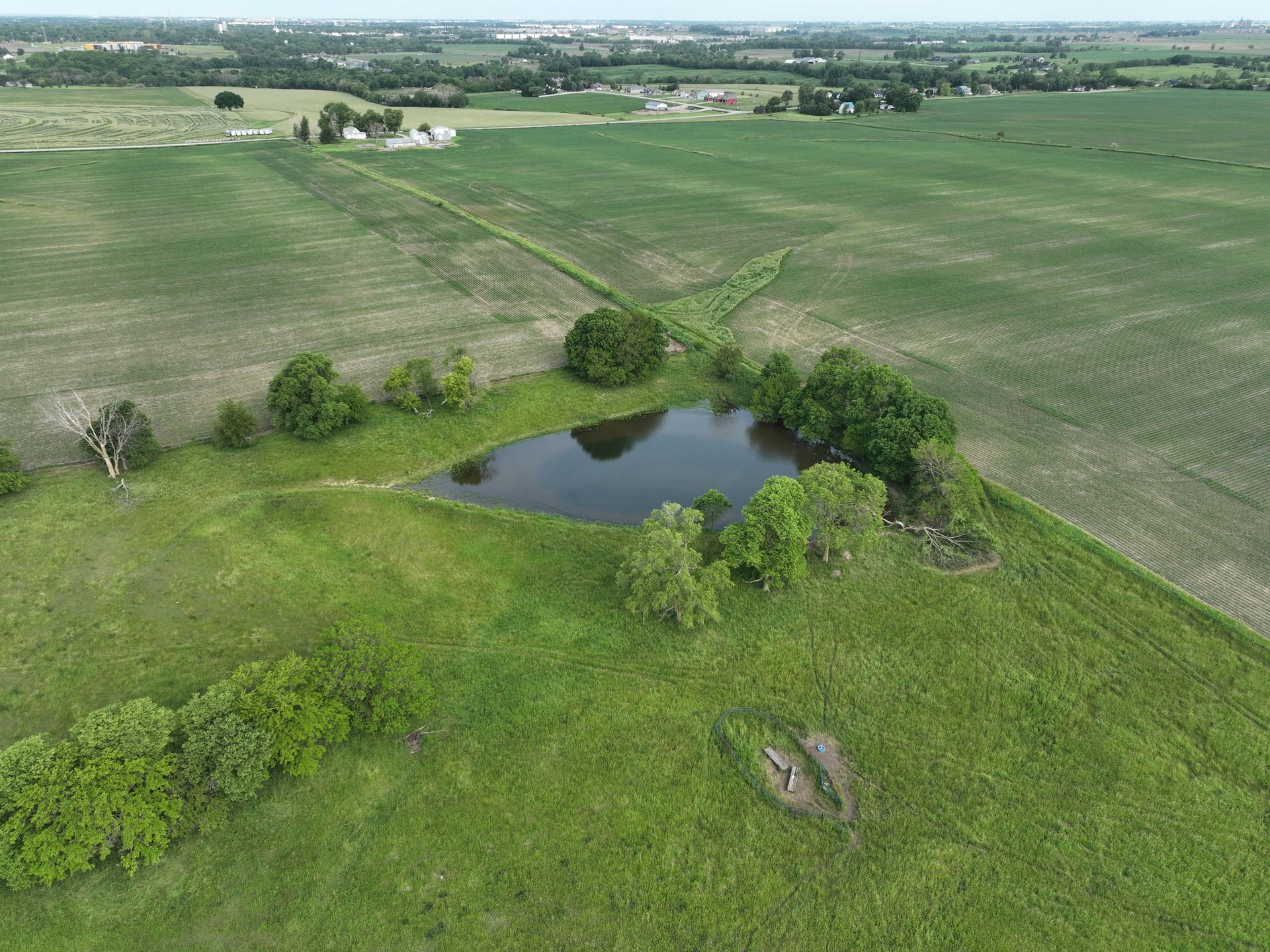 An aerial view of a field with a small pond in the middle