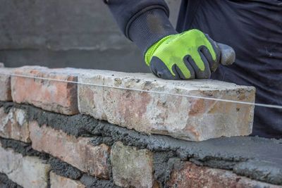 Man Installing Brick and Building a Brick Wall — Lincoln Park, MI — Dix Block and Supply Company Inc.