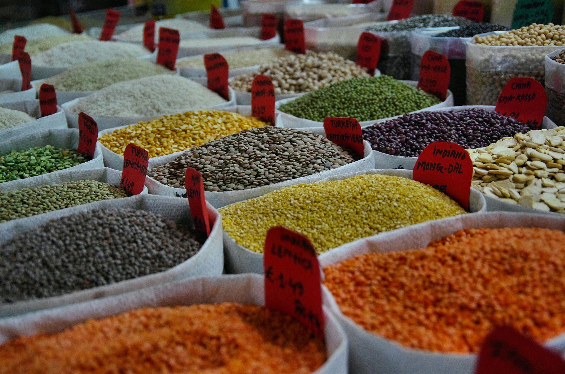A variety of grains and spices are lined up on a table.