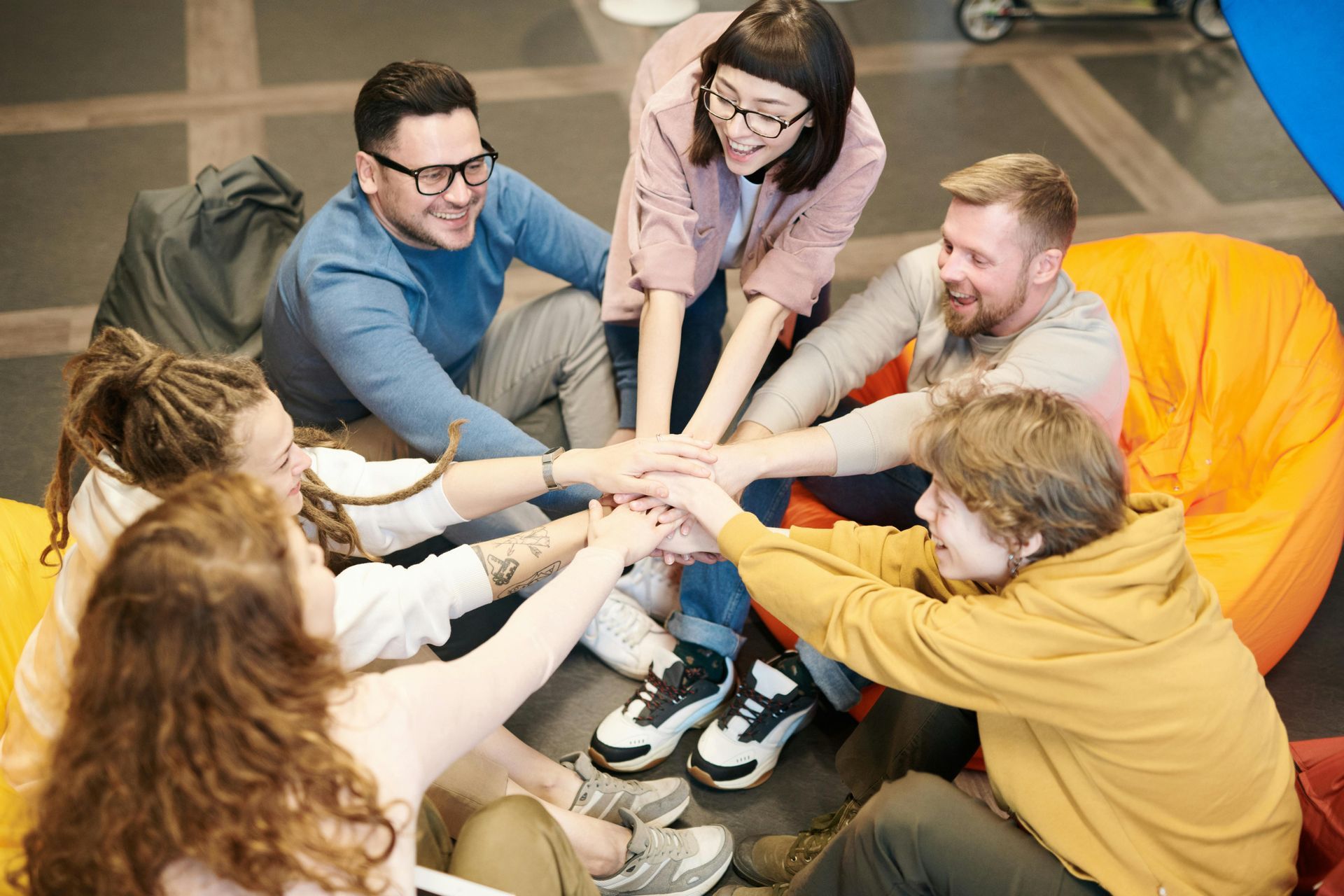 A group of people are sitting in a circle putting their hands together.