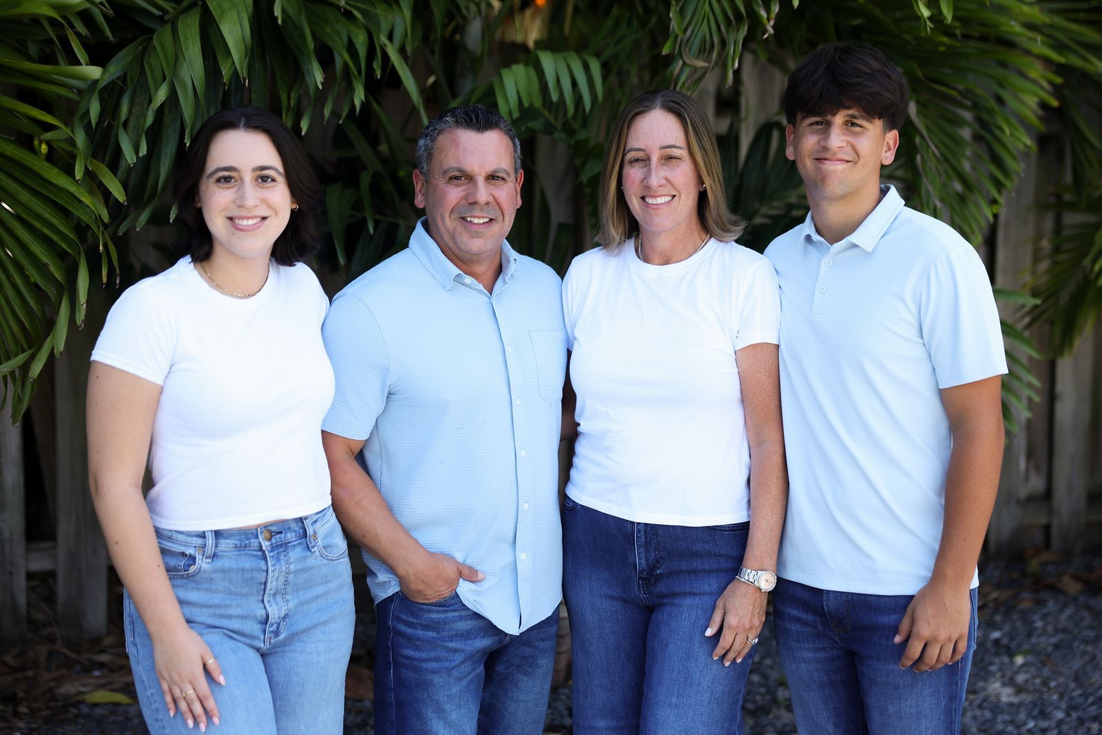 A family is posing for a picture together in front of a palm tree.